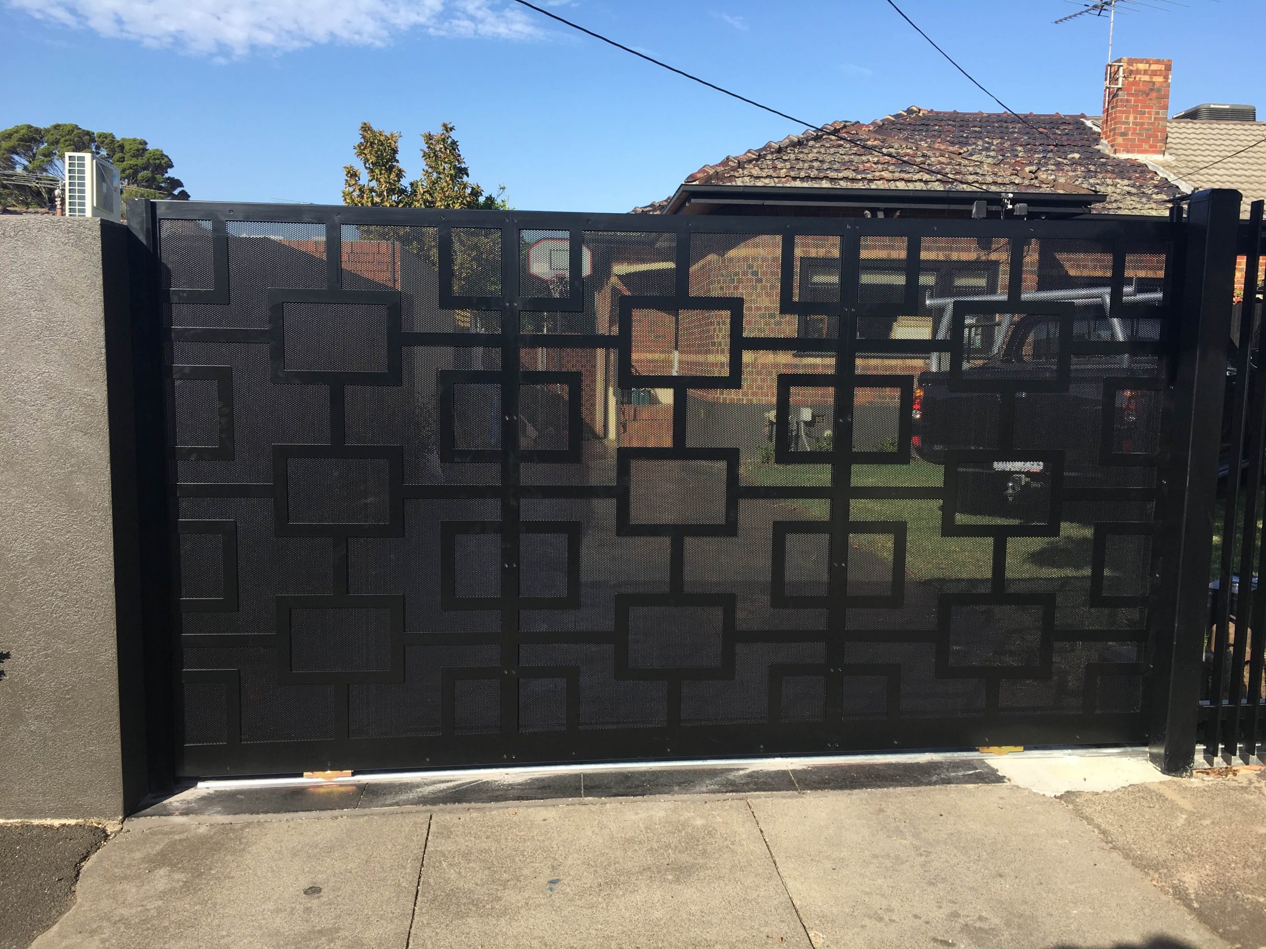 Black aluminium sliding gate with custom geometric mesh design at a Melbourne home