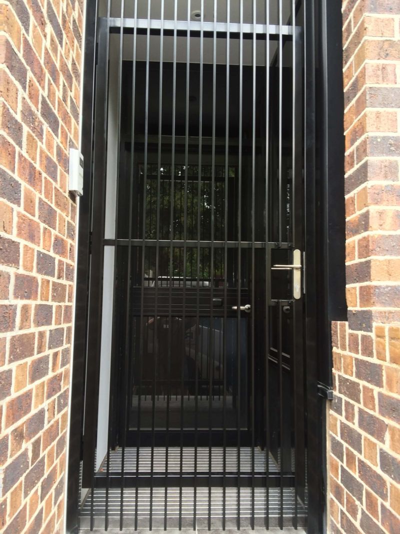 Black vertical bar security gate installed at a brick entryway in Melbourne, providing secure access.