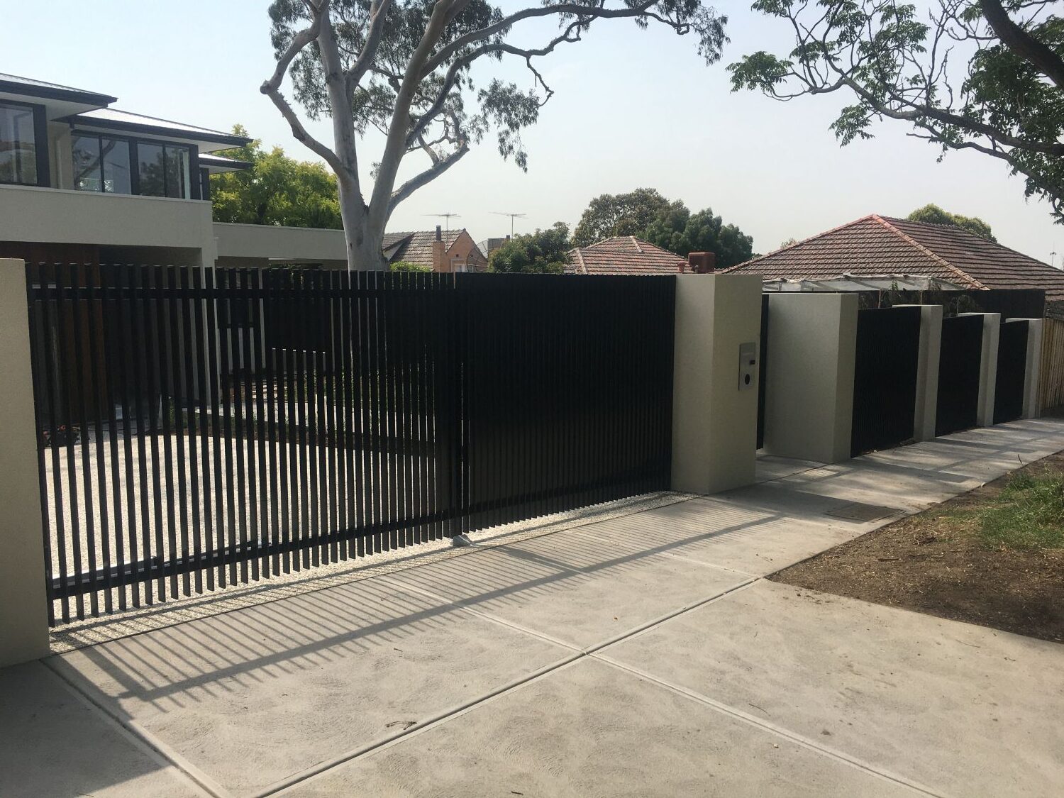Custom black steel fence infills and automated double gates installed at a modern Kew home