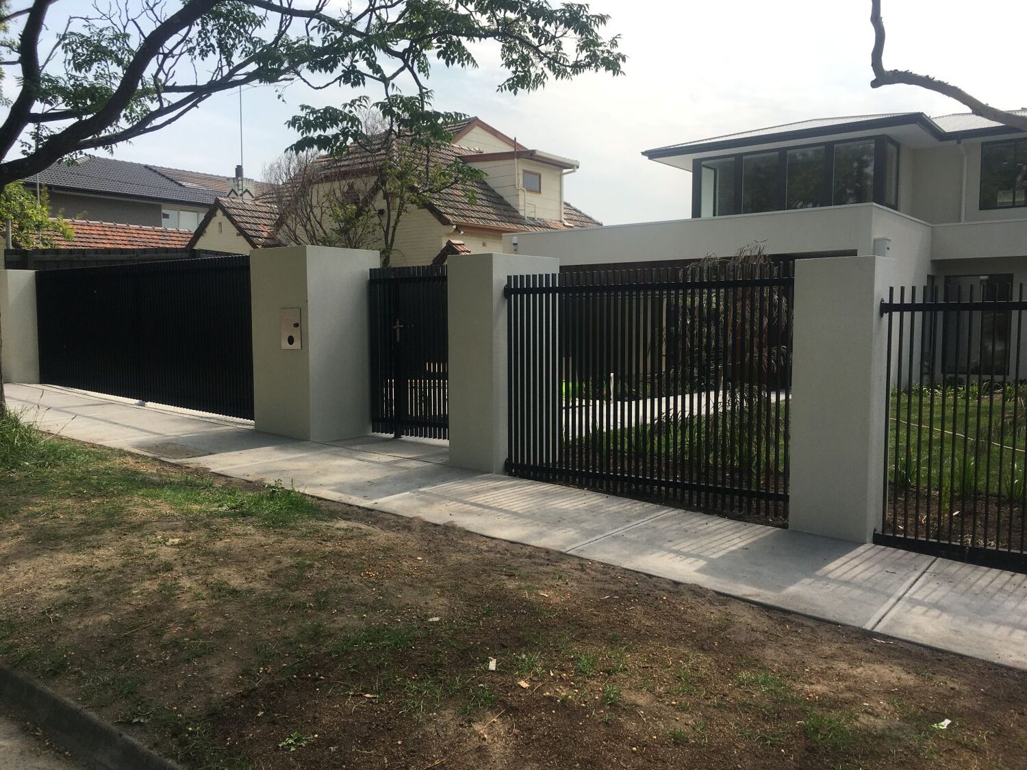 Black steel automated driveway gates with matching fence infills for a residential property in Kew