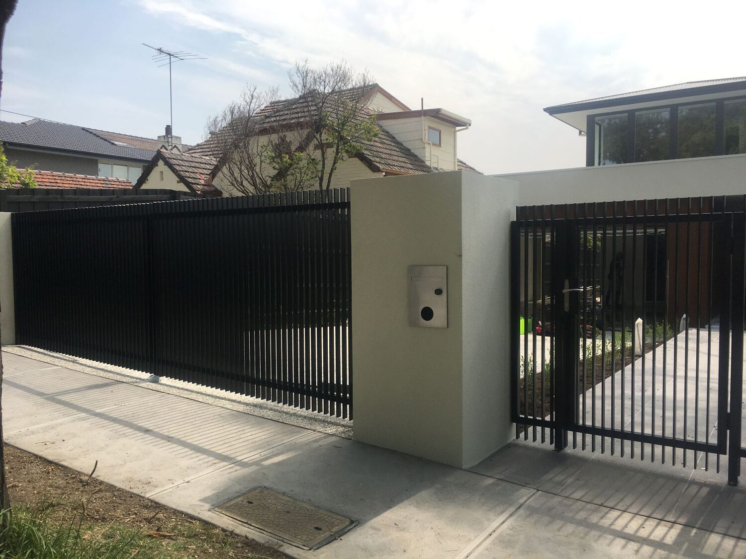 Custom black steel pedestrian gate, intercom pillar and automated driveway gates in Kew