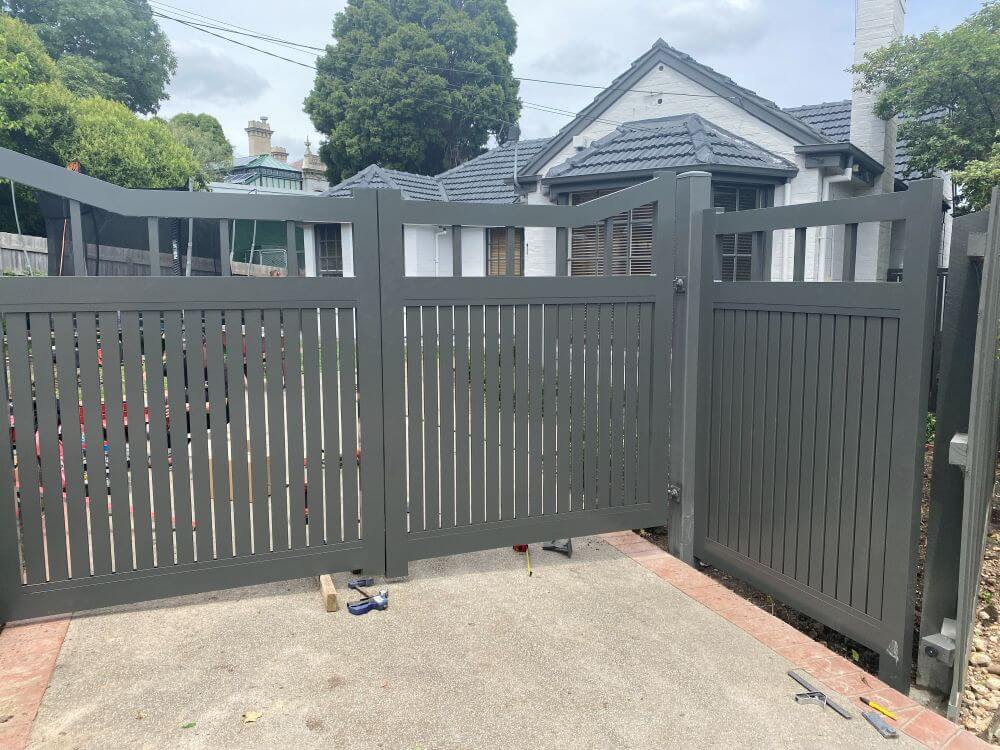 Closed powdercoated Monument double driveway gates with vertical blades and matching side infill panel in Ivanhoe.