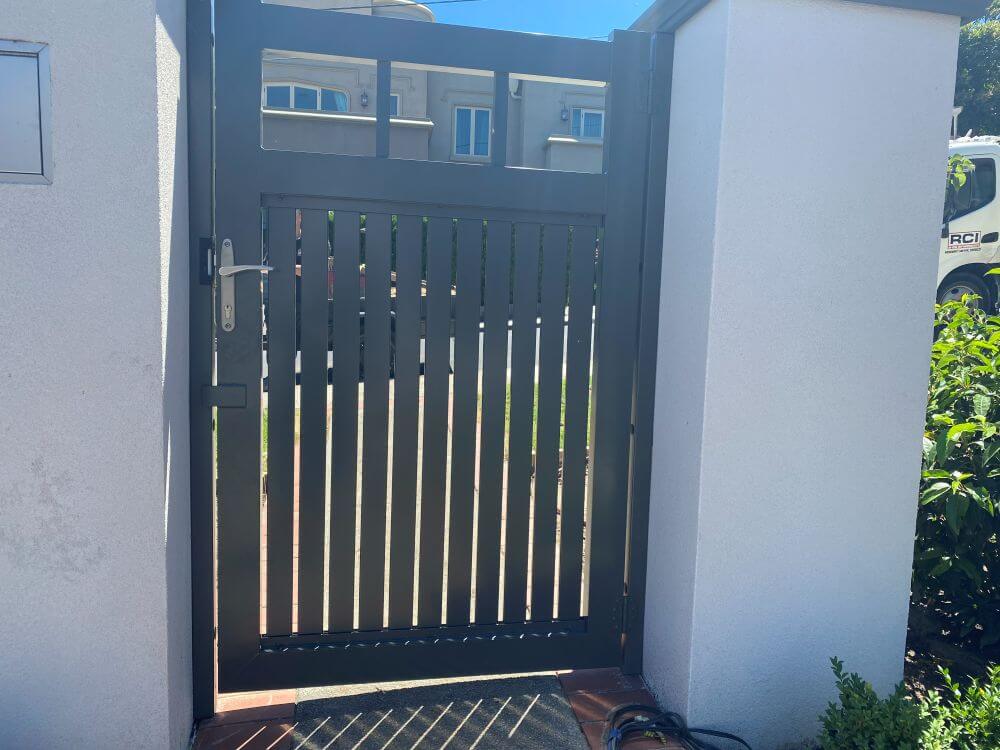 Close-up view of a Hampton-style aluminium pedestrian gate featuring lever handle hardware and open top detailing.
