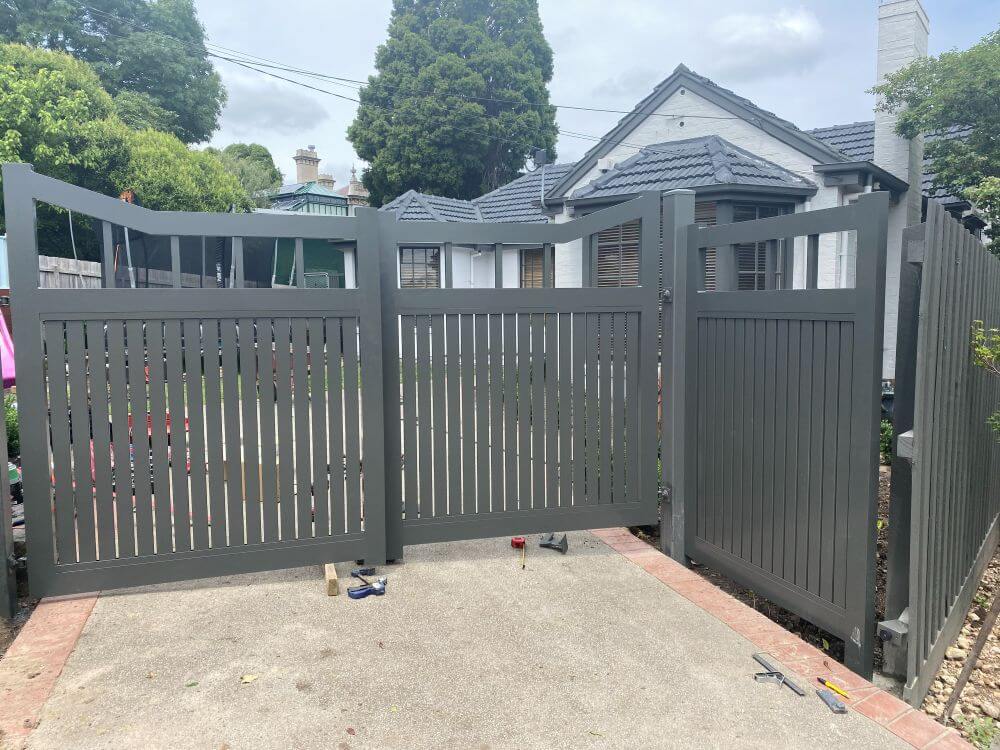 Front view of open Monument aluminium double swing driveway gates with vertical blades and open rectangular top detailing.