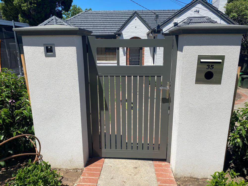 Powdercoated Monument pedestrian entry gate installed between white rendered pillars with integrated letterbox in Ivanhoe.